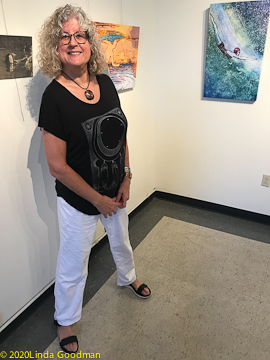 Photo of Linda Goodman in front of her artist statement at her exhibit Water Bodies